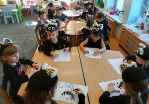 Dzieci przy stolikach rysują węglem.